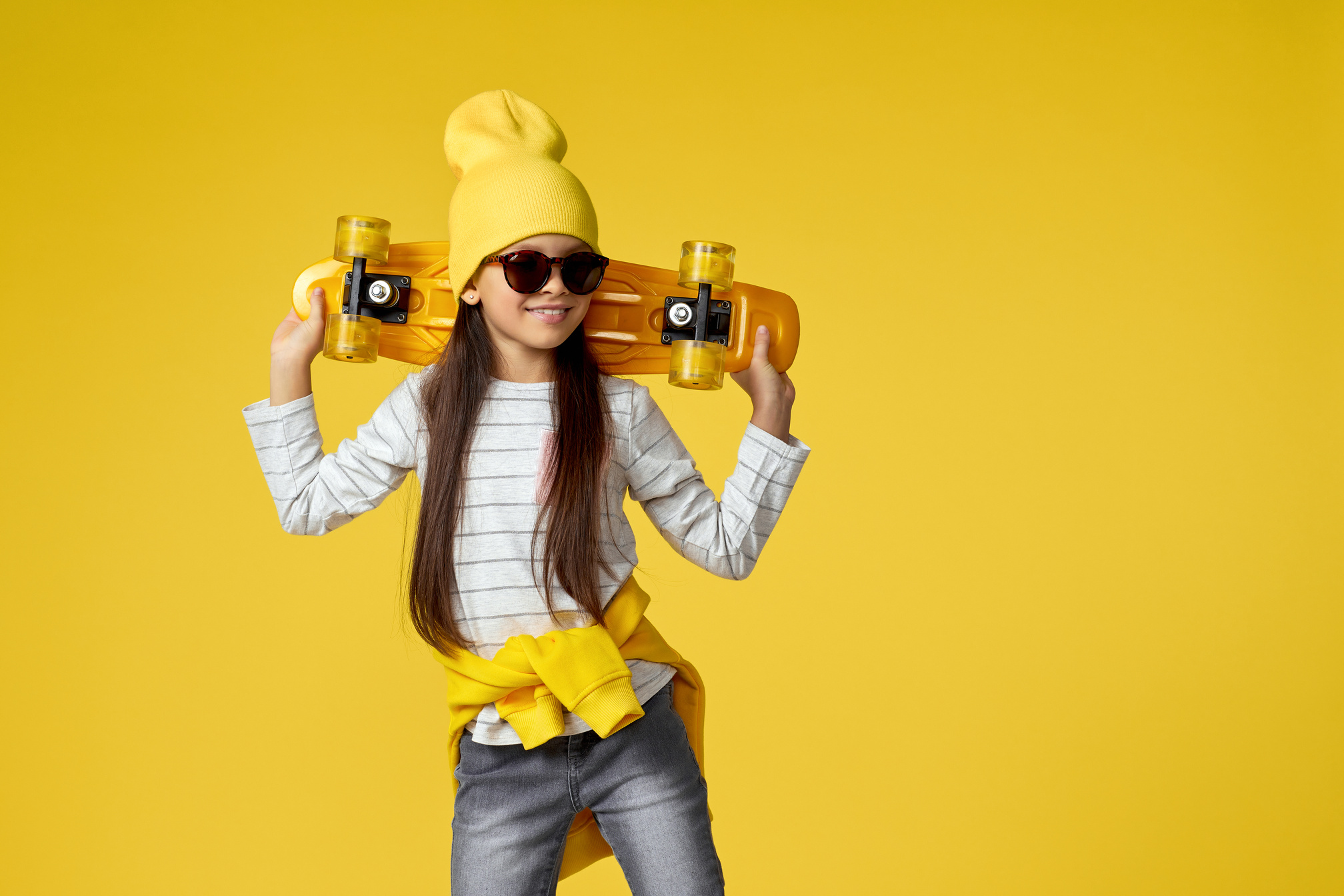 Girl in Sunglasses and Yellow Hat with Yellow Skateboard